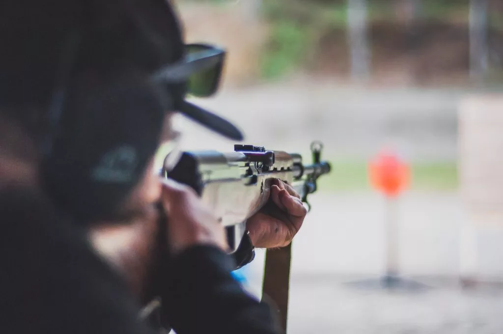 A photo of a man shooting a gun at a target. 