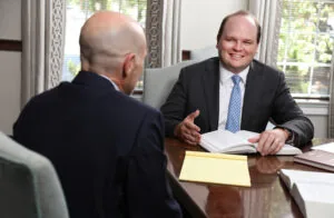 A photo of BBGA personal injury attorney Chase Ruffin who is sitting at a conference table with a client. 